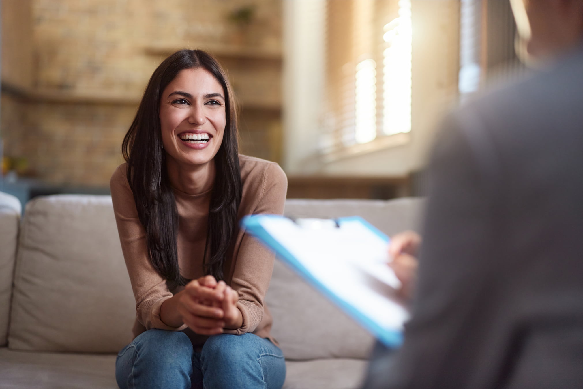 Young happy woman communicating with a therapist during a home visit.
