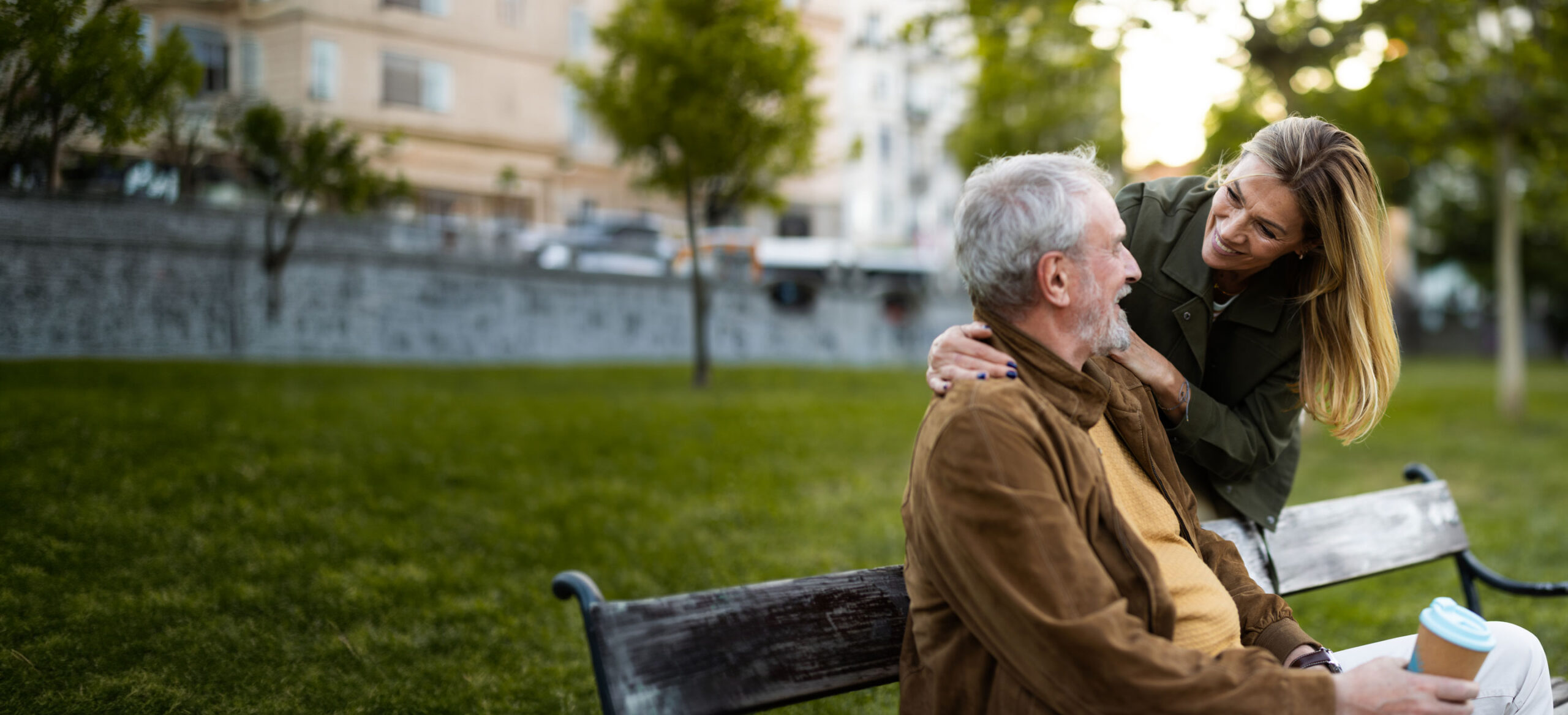 A happy elderly man sitting on a bench with his affectionate daughter, enjoying a conversation in the park